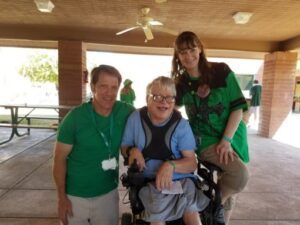 Three people smiling in a covered outdoor area.
